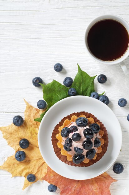 Gâteau aux bleuets avec des baies fraîches et une tasse de café et des feuilles d'érable d'automne