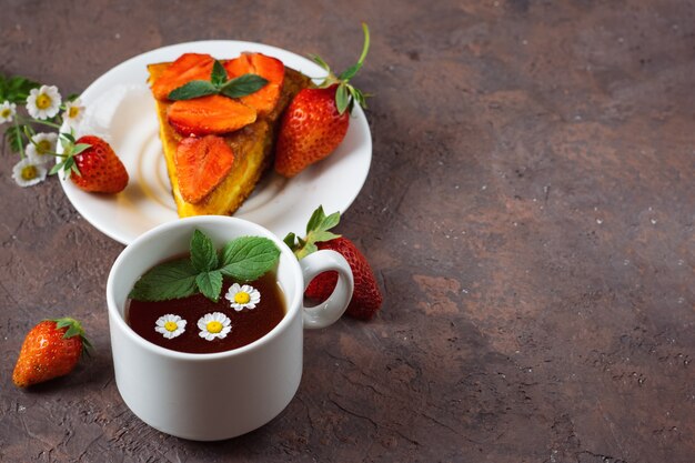 Gâteau aux carottes très savoureux décoré de fraises et d'une tasse de thé aux fleurs parfumées