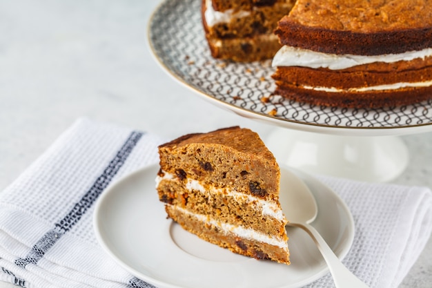 Gâteau aux carottes végétalien à la crème de noix de coco, fond blanc.