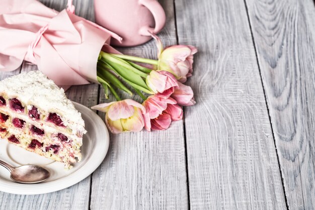 Un gâteau aux cerises et aux tulipes roses sur une table en bois blanche