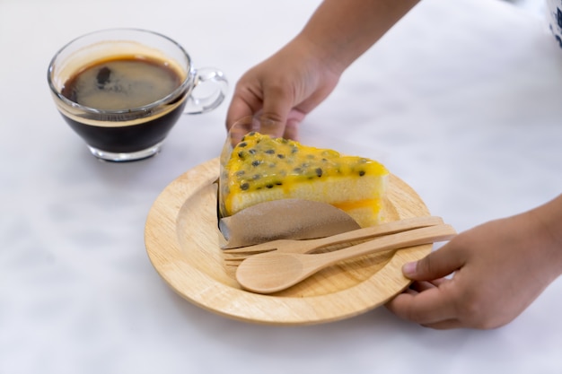 Gâteau aux fruits de la passion sur une assiette en bois à la main