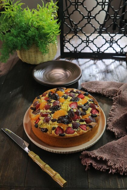 Photo gâteau aux fruits sur table en bois avec fond de verdure