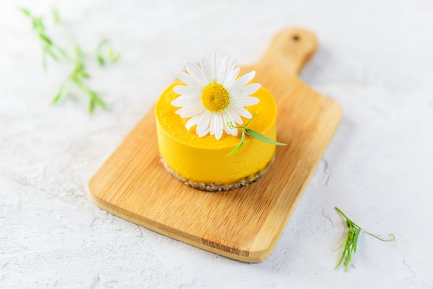 Gâteau aux noix de cajou à l'argousier à la camomille sur une planche de bois.