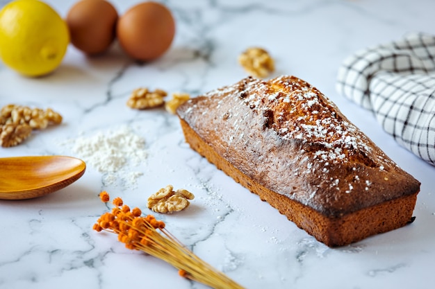 Gâteau aux noix fait maison et ingrédients cuisson concept sur marbre blanc