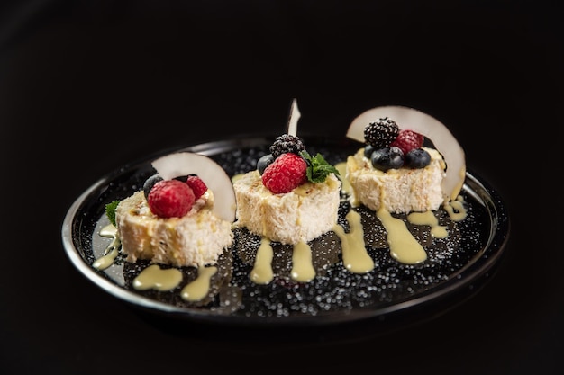 Gâteau aux trois chocolats avec des gouttes de chocolat sur fond noir Gâteau en couches avec soufflé au chocolat au lait noir et blanc décoré de fraises sur le dessus Fond de confiserie avec espace de copie