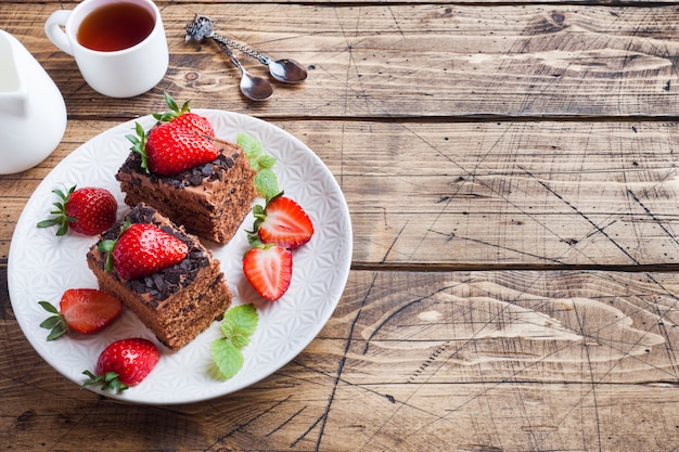 Gâteau aux truffes au chocolat avec fraises et menthe. Table en bois. Espace copie