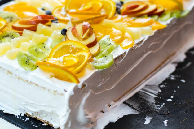 Gâteau blanc aux fruits. Morceaux de pomme et de kiwi. Pâte molle et crème au beurre. Plat de fête sucré.