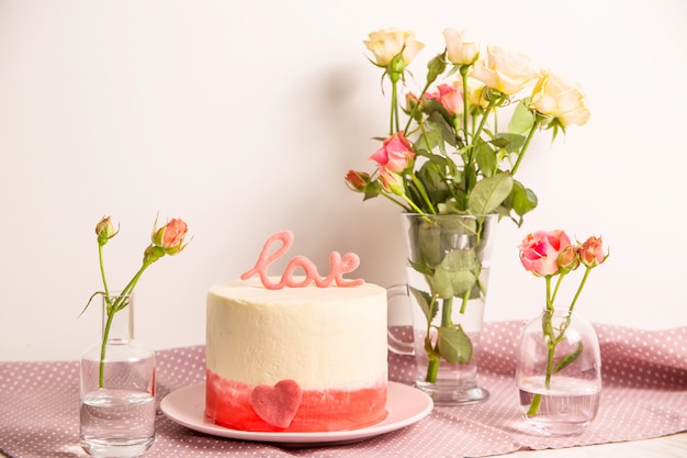 Gâteau Blanc à Décor Rose Et Le Mot Amour Au Sommet Parmi Les Petites Roses Blanches Et Roses