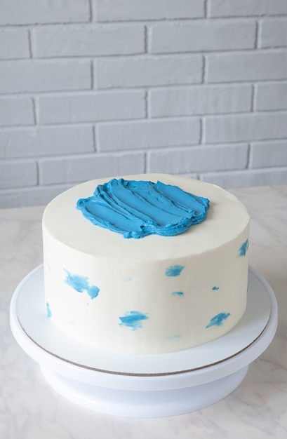 Gâteau blanc simple avec décor bleu sur table avec espace de copie.