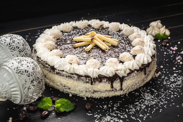 Gâteau blanc sucré au chocolat et meringue sur le fond en bois noir