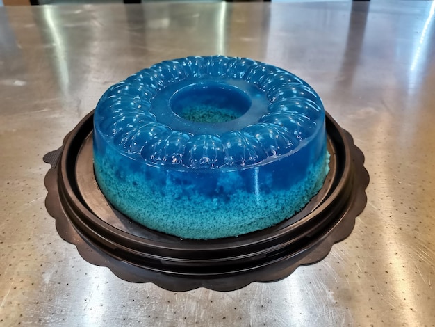 Un gâteau bleu avec un anneau bleu posé sur une surface noire.