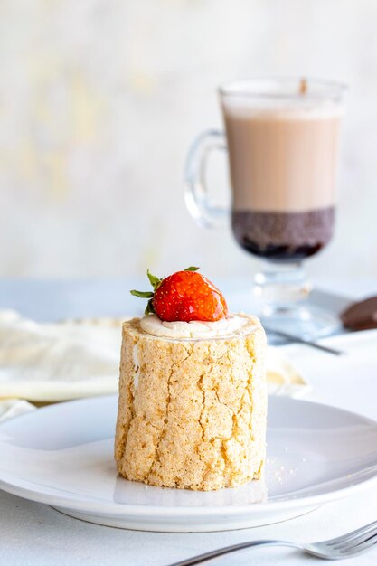 Gâteau bûche aux fraises sur fond blanc avec du chocolat chaud sur le côté gros plan