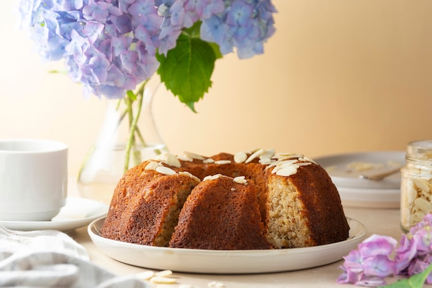 Gâteau bundt traditionnel, gâteau rond cuit au four avec une tasse de café et des fleurs en arrière-plan. Recette pas à pas.