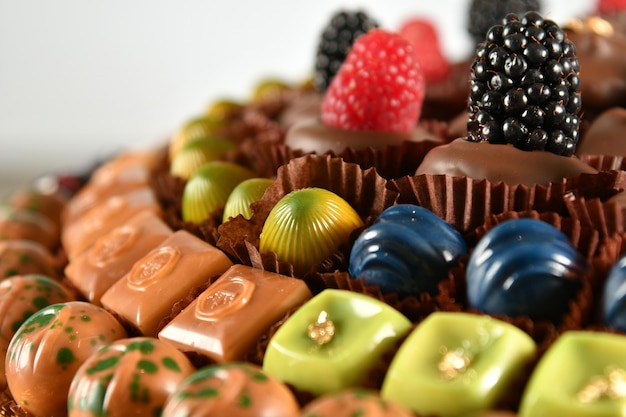 Un gâteau avec des chocolats et des framboises dessus