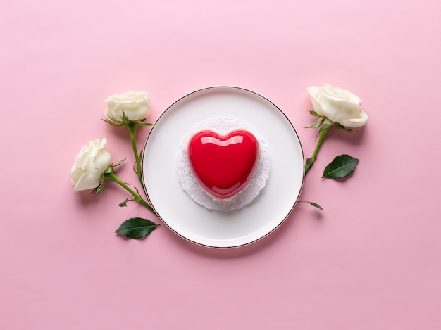 Gâteau coeur rouge sur assiette et roses délicates