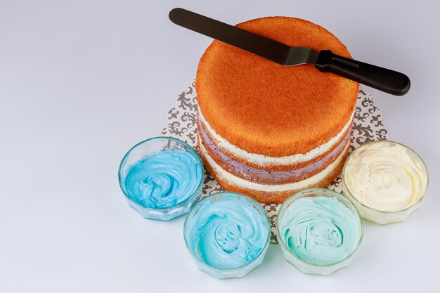 Gâteau en couches éponge avec spatule et quatre bols à glaçage