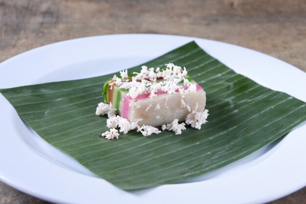 Gâteau en couches et noix de coco râpée sur une assiette avec feuille de bananier, nourriture malaise