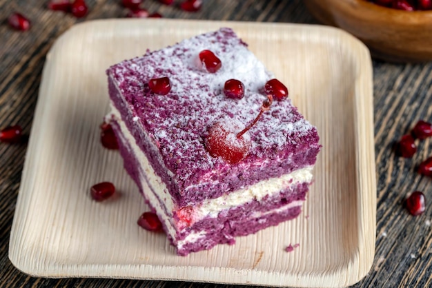 Un gâteau de couleur marron avec le goût de différentes baies et une garniture au lait crémeux de fromage cottage avec des graines de grenade