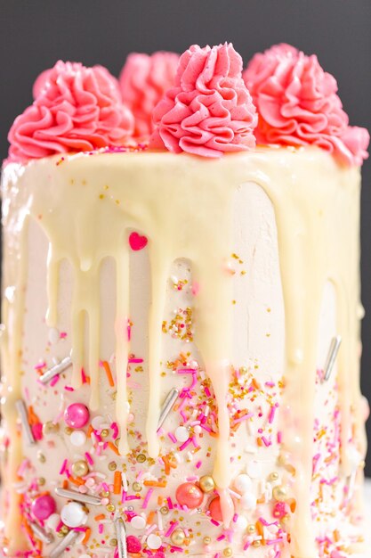 Gâteau à la crème au beurre rose et blanc avec pépites roses et goutte de ganache au chocolat blanc.