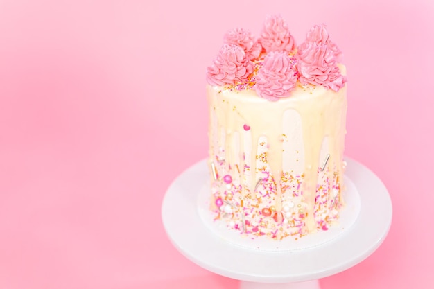 Gâteau à la crème au beurre rose et blanc avec pépites roses et goutte de ganache au chocolat blanc.