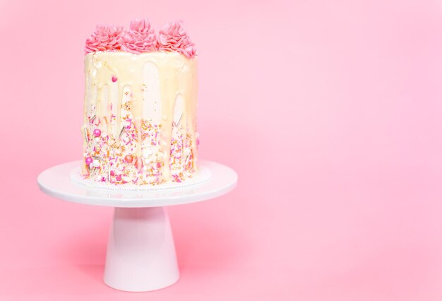 Gâteau à la crème au beurre rose et blanc avec pépites roses et goutte de ganache au chocolat blanc.