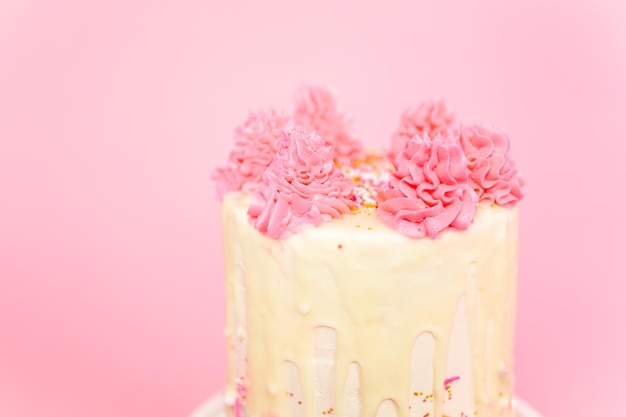 Gâteau à la crème au beurre rose et blanc avec pépites roses et goutte de ganache au chocolat blanc.