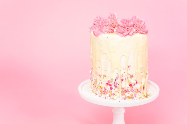 Gâteau à la crème au beurre rose et blanc avec pépites roses et goutte de ganache au chocolat blanc.