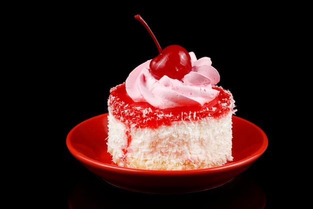 Gâteau à la crème et cerise sur une soucoupe rouge et café