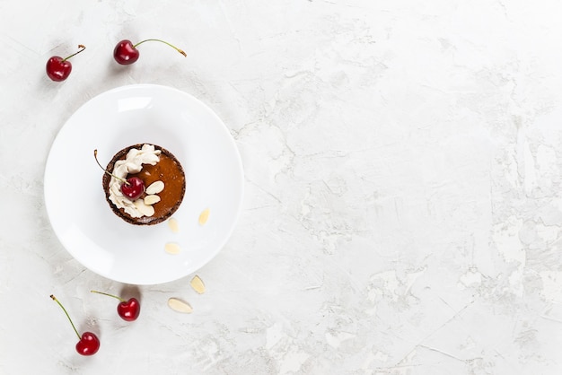 Gâteau à la crème de coco, cerises et amandes sur une planche de bois