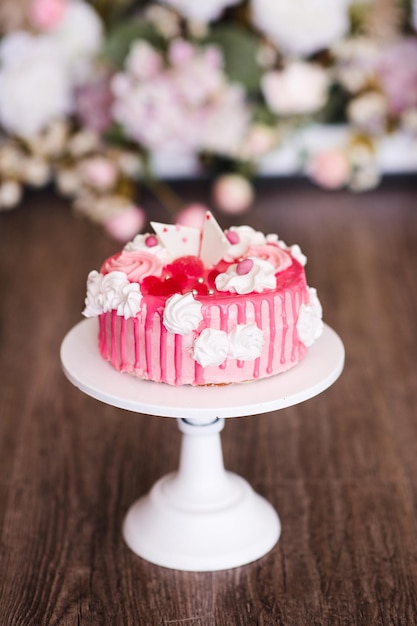 Gâteau crémeux rose sur stand blanc libre