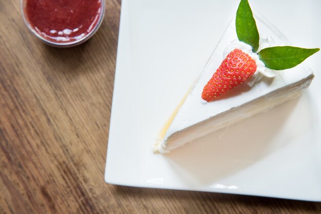 Gâteau de crêpe aux fraises en plaque blanche en vue de dessus sur bois