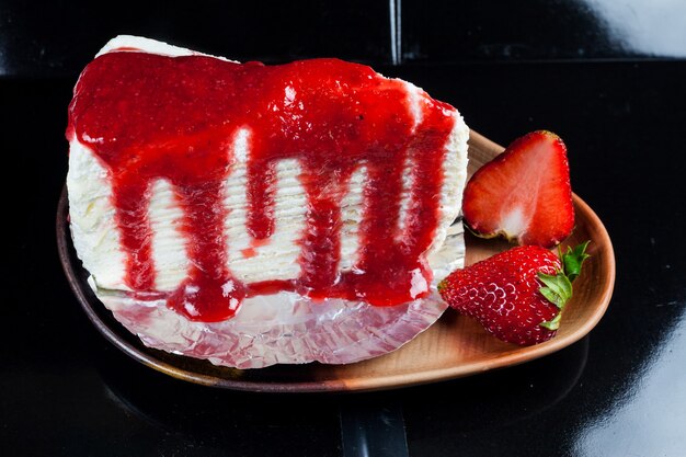 Gâteau de crêpe avec sauce aux fraises et fraises fraîches.