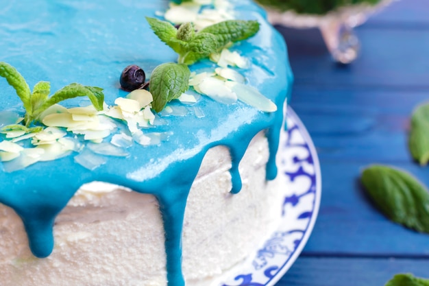 Gâteau décoré de crème bleue, de menthe et de bleuets.