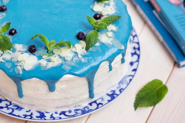 Gâteau décoré de crème bleue, de menthe et de bleuets.