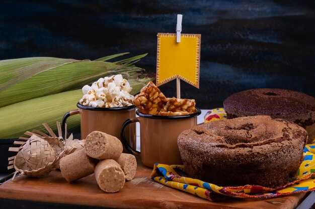 Gâteau de drapeau en papier pop-corn et bonbons de festa junina sur une table en bois noire
