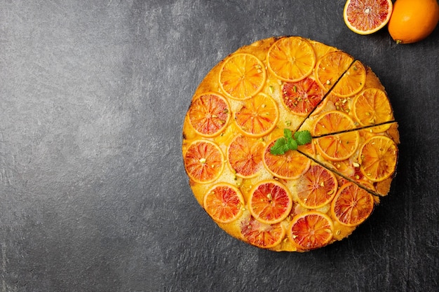 Gâteau à l'envers à l'orange sanguine et à la polenta à la pistache sur une surface en pierre sombre