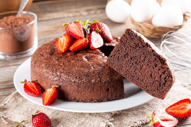 Gâteau éponge au chocolat rond fait maison ou gâteau en mousseline si doux et délicieux avec des fraises. Concept de boulangerie maison pour le fond et le papier peint