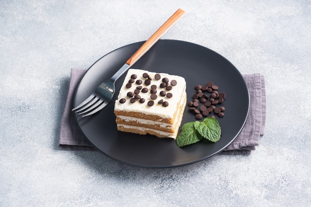 Gâteau éponge avec crème au beurre et morceaux de chocolat à la menthe sur une plaque noire. Dessert pour célébrer un événement ou une fête d'anniversaire. vue de dessus, copiez l'espace.