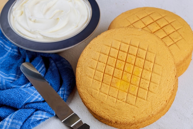 Gâteau éponge, glaçage et spatule pour faire un gâteau de mariage.