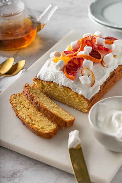 Gâteau éponge à l'orange garni d'oranges sanguines fraîches et de crème. Verticale