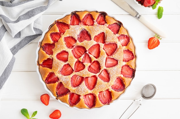 Gâteau éponge ou tarte à la vanille aux fraises sur un fond en bois blanc avec des fraises fraîches