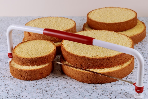 Gâteau éponge en tranches avec niveleur sur table pour faire un gâteau de mariage