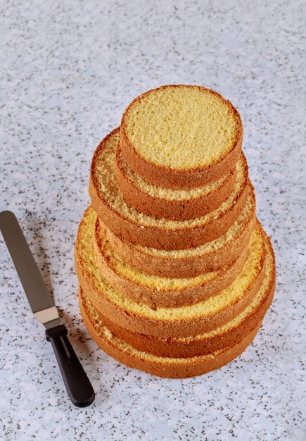 Gâteau éponge en tranches avec une spatule sur la table pour faire un gâteau de mariage