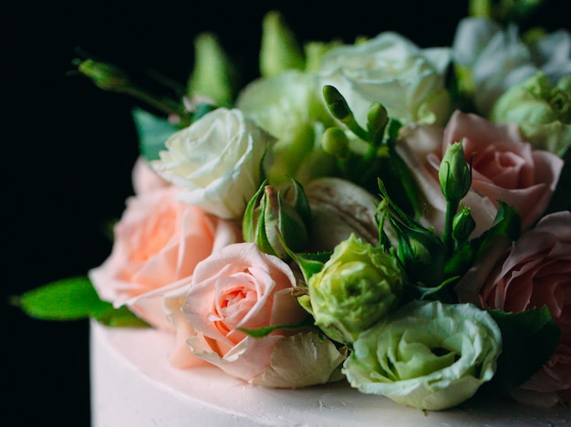 Le gâteau est décoré de fleurs sur un fond sombre.