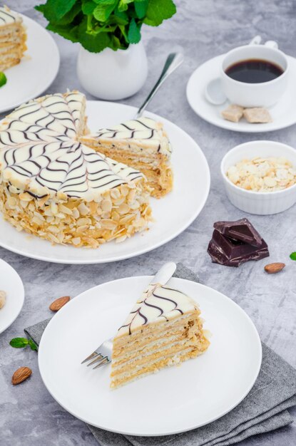 Gâteau Esterhazy hongrois sur une assiette blanche avec une tasse de café à la menthe et des amandes