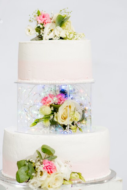 Gâteau étagé pour mariage ou anniversaire. Beau gâteau de fête blanc et rose décoré de fleurs.