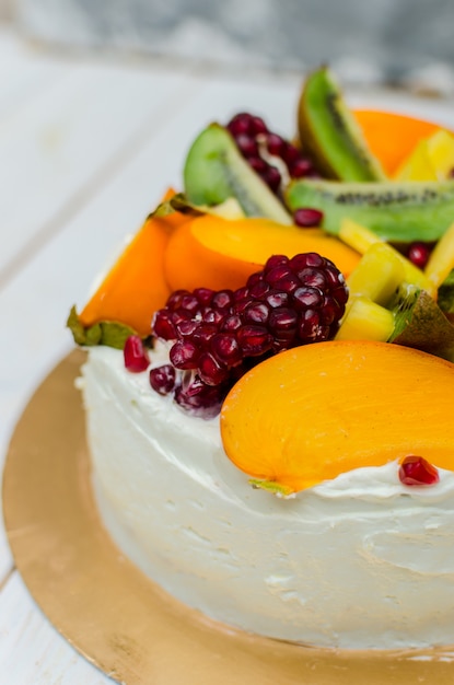 Gâteau exotique. Gâteau éponge à la crème blanche et beaucoup de fruits (kiwi, grenade, kaki, mangue)