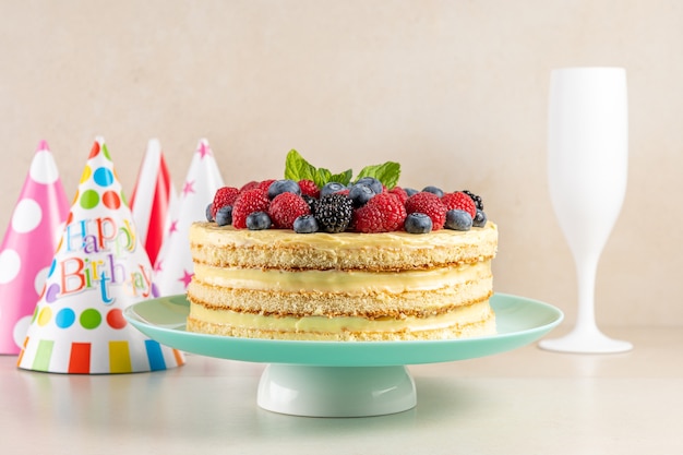 Gâteau fait maison avec des baies fraîches et un chapeau d'anniversaire