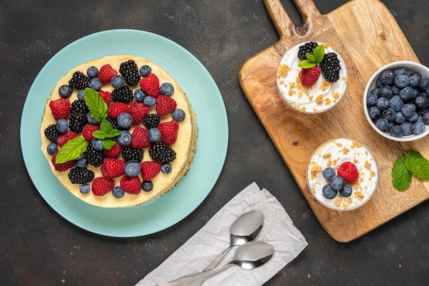 Gâteau fait maison avec des baies fraîches et des desserts sucrés sur une surface sombre.