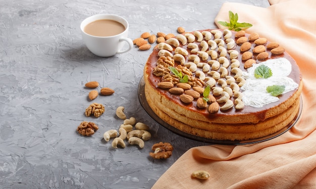 Gâteau fait maison avec de la crème au caramel et des noix avec une tasse de café sur un fond de béton gris